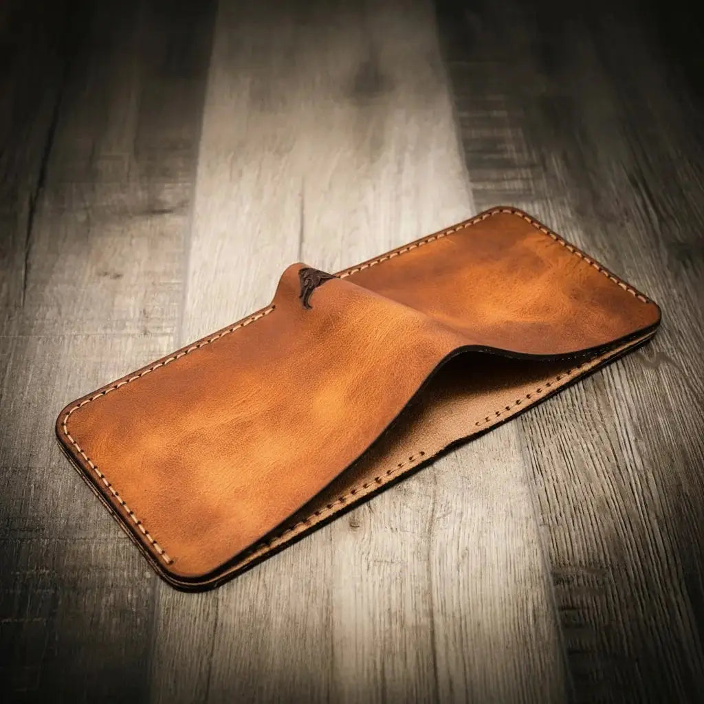 Brown leather bifold wallet with stitching on a wooden background