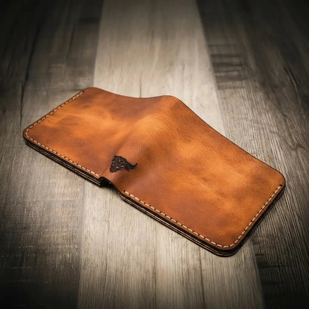 Brown leather bifold wallet with stamped bull logo on wooden surface.