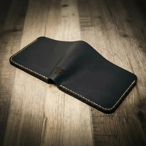 Dark leather bifold wallet with tan stitching and a bull head emblem.