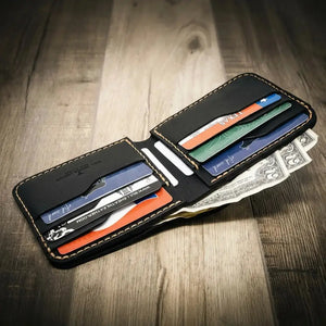 Black leather bifold wallet open with card slots and US dollar bills on wood