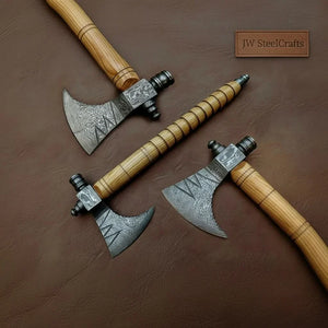 Damascus steel axe head with wood handle on rustic wood surface
