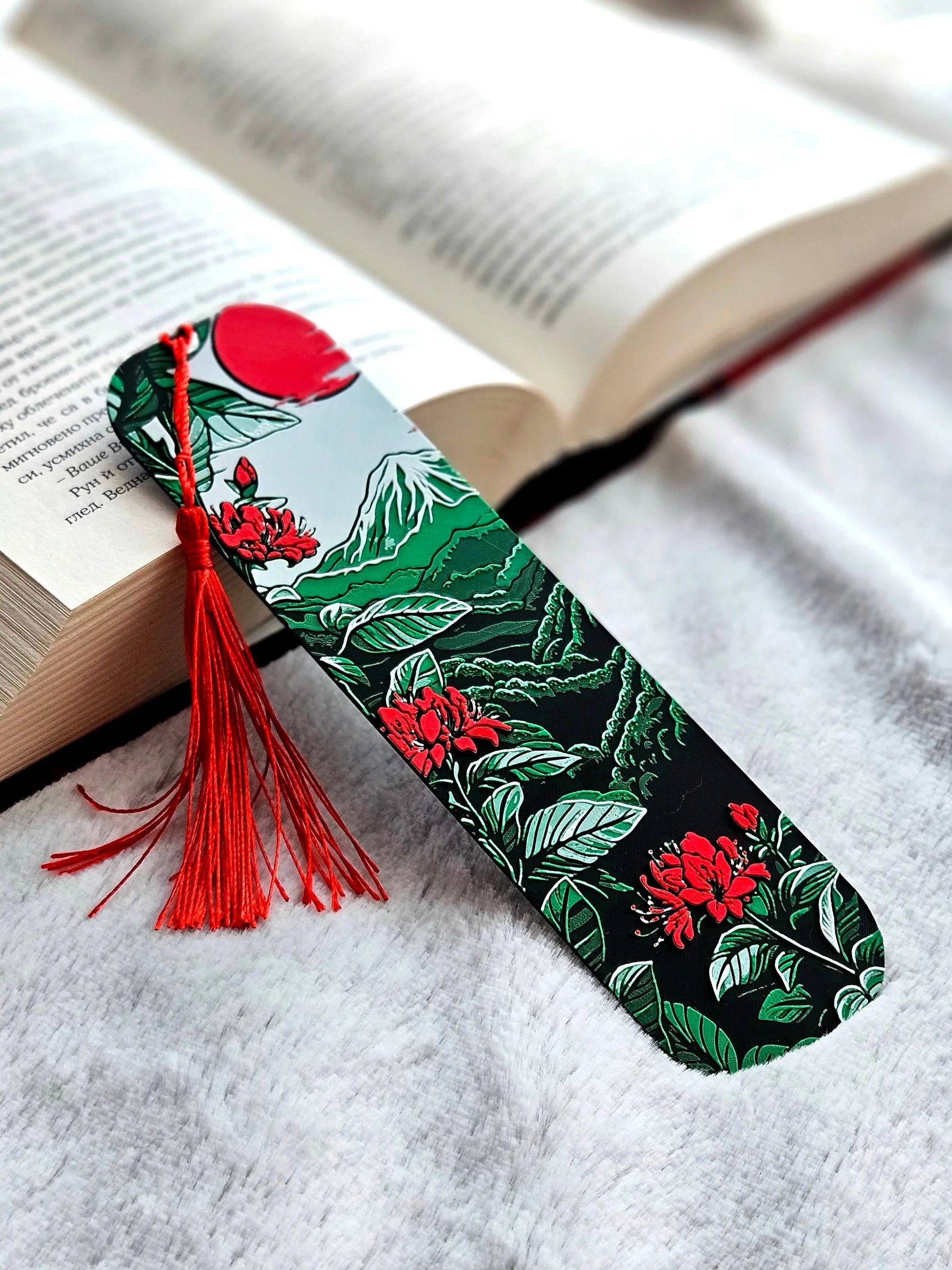 Bookmark with Japanese design featuring Mount Fuji, red sun, flowers, foliage, and a red tassel on a book.
