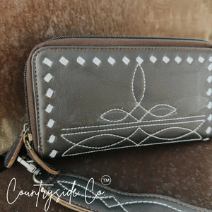 Brown leather wristlet wallet with white boot stitching and detachable strap.