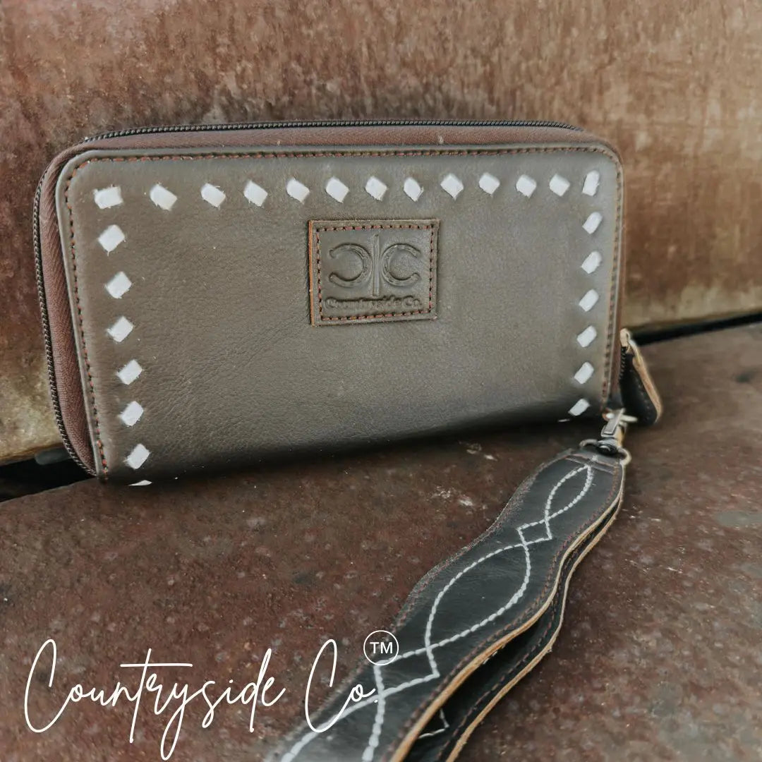 Brown leather wallet wristlet with boot stitch detail and zipper closure.
