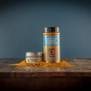Bourbon Smoked Curry Powder in tin and shaker with spilled curry powder