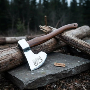 Damascus steel axe head with wood handle on rustic wood surface