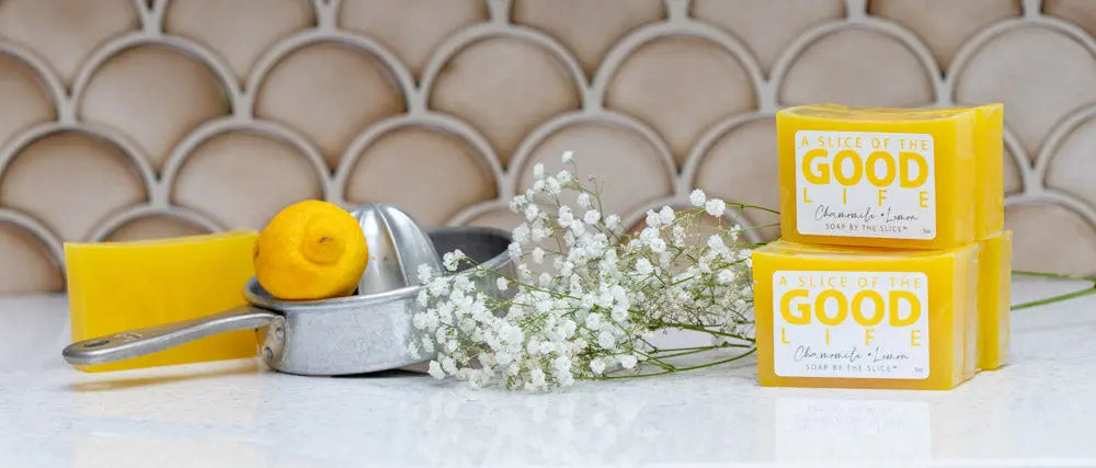 Yellow chamomile lemon bar soaps stacked next to a lemon and juicer.