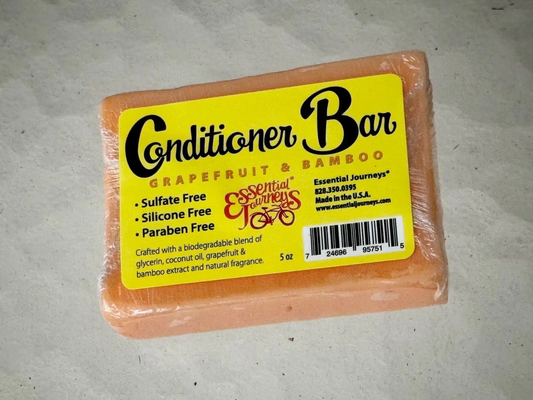 Orange conditioner bar with yellow label listing ingredients and brand Essential Journeys.