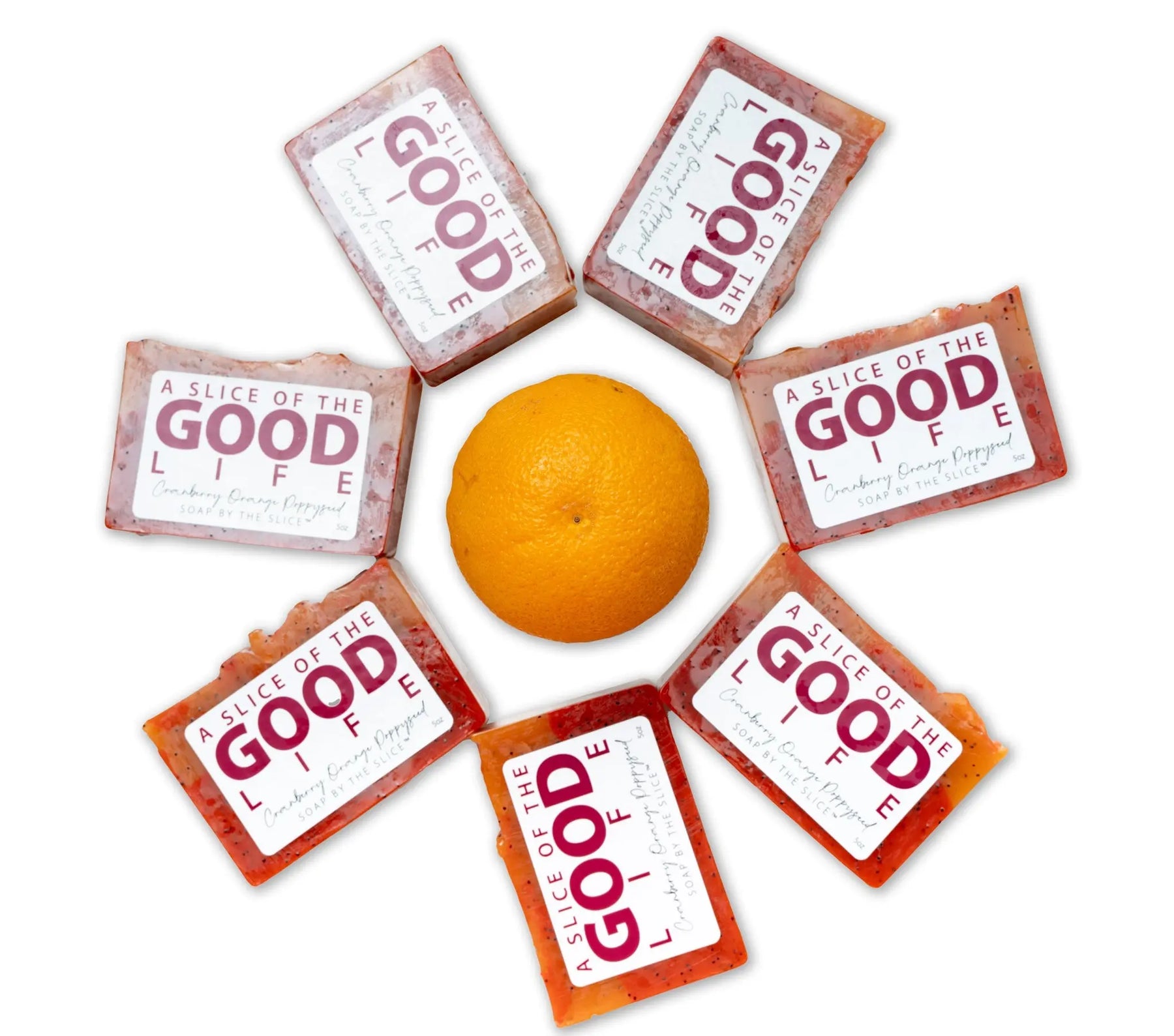 Cranberry orange poppyseed soap bars arranged around a whole orange.