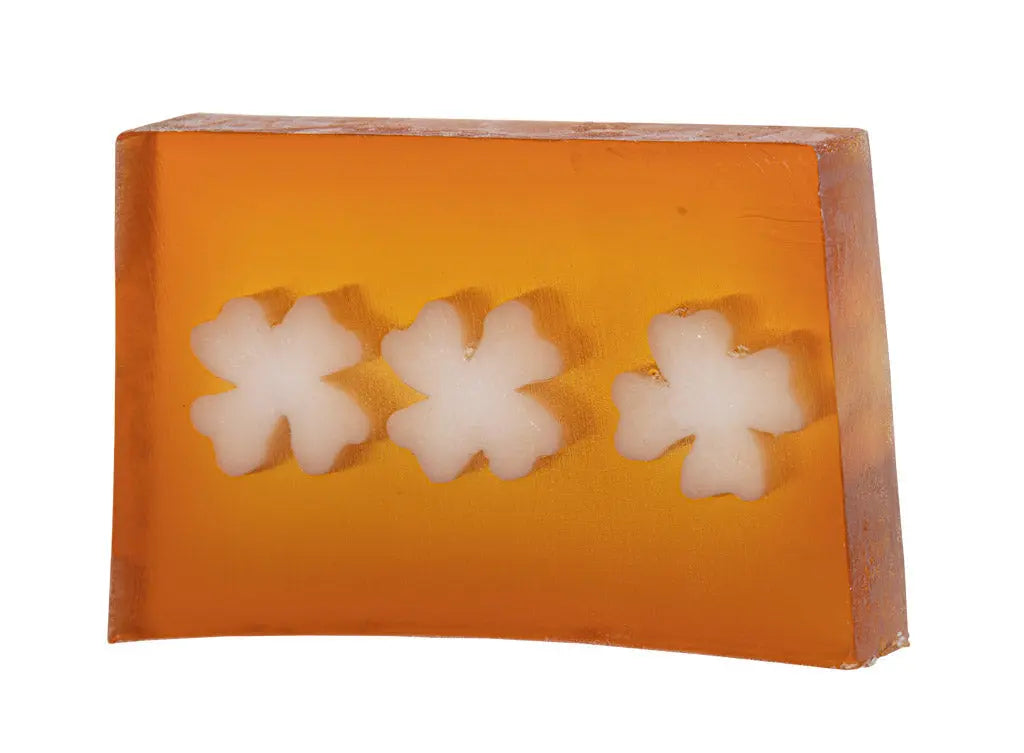 Orange soap slice with three white shamrock shapes embedded inside.