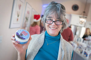 Woman holding a round container of Crotch Grease anti-chafing balm.