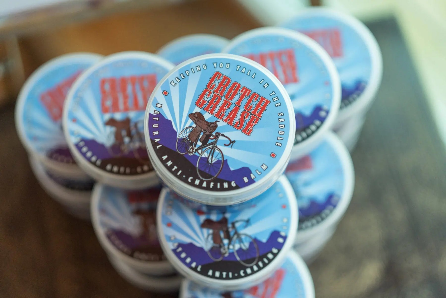 Stack of Crotch Grease anti-chafing balm tins with visible branding