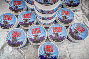 Round containers of Crotch Grease anti-chafing balm with bicycle and saddle graphics.
