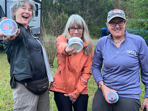 Three women hold containers of Crotch Grease.
