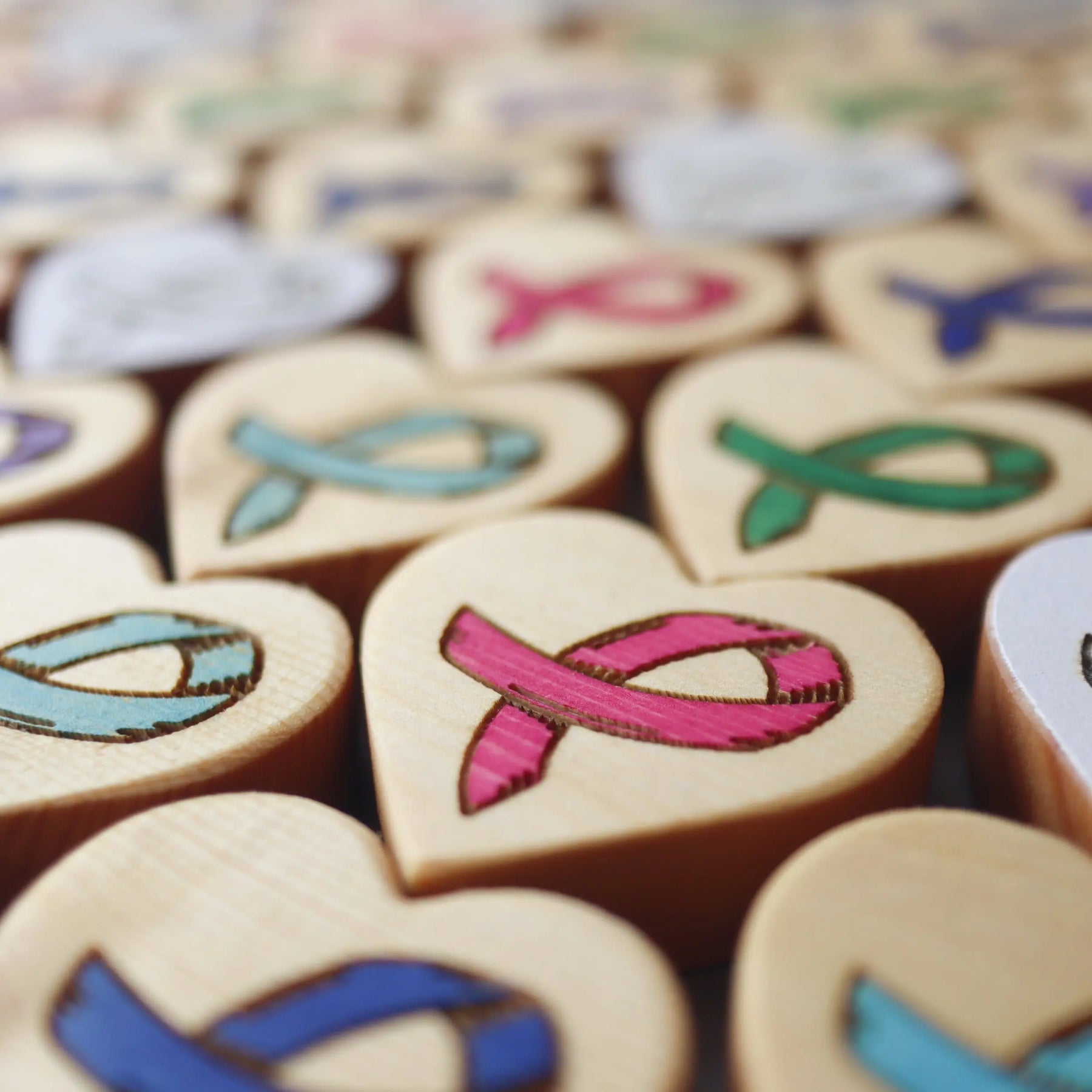 Wooden heart shapes with carved cancer awareness ribbons in various colors.