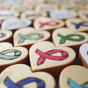 Wooden heart shapes with carved cancer awareness ribbons in various colors.