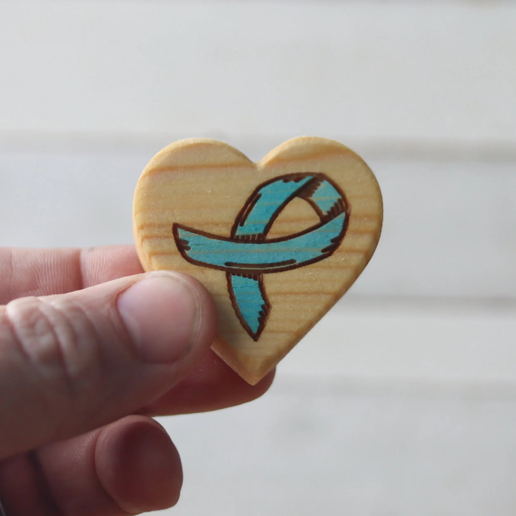 Wooden heart charm with a teal awareness ribbon design.