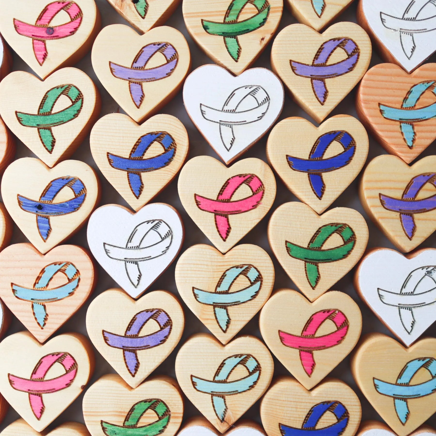 Wooden heart shapes with colorful ribbon designs for cancer awareness.