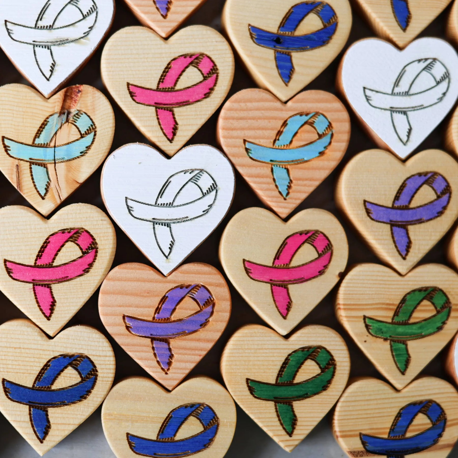 Wooden heart shapes with engraved awareness ribbons in various colors.