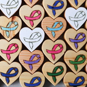 Wooden heart shapes with engraved awareness ribbons in various colors.