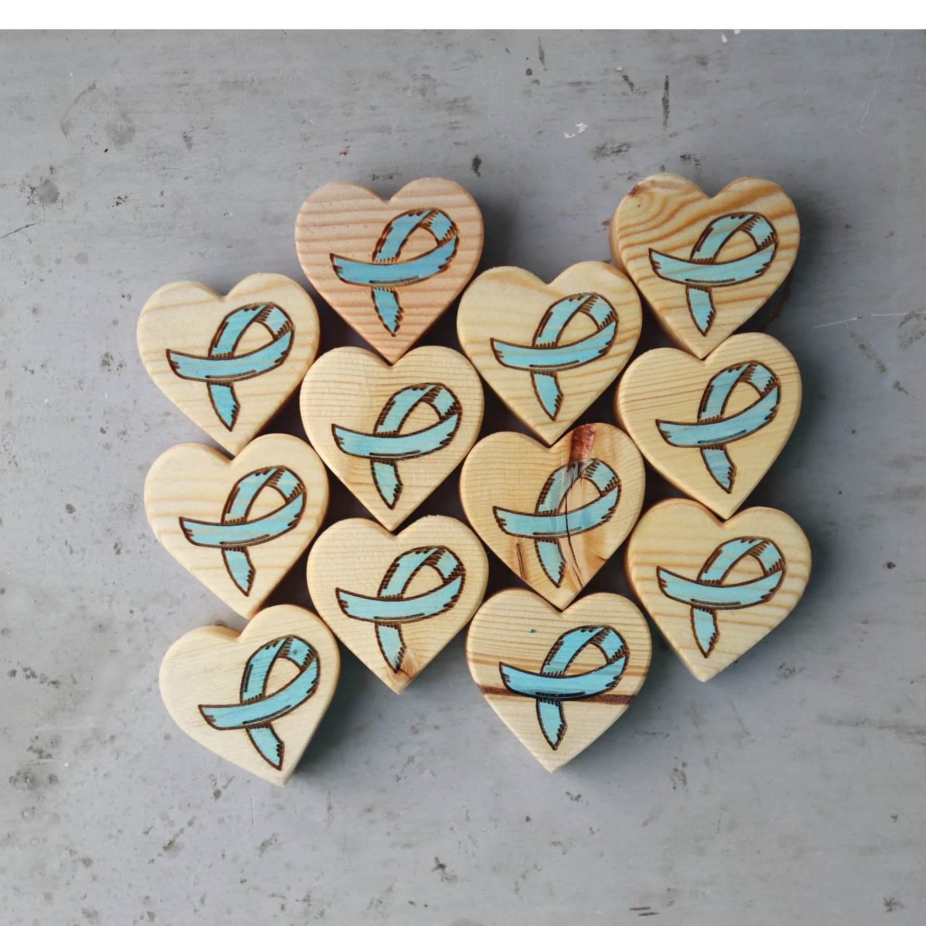 Wooden hearts with engraved blue awareness ribbons.