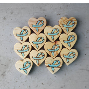 Wooden hearts with engraved blue awareness ribbons.
