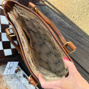 Interior of a brown cowhide purse with Countryside Co. logo lining and pockets.