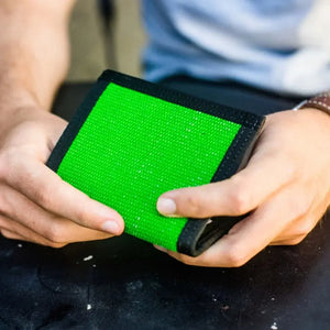 Person holding a bright green wallet with black trim in their hands.