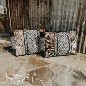 Two Charlene Cowhide Weekender Bags by Countryside Co. with geometric textile patterns and leather handles.