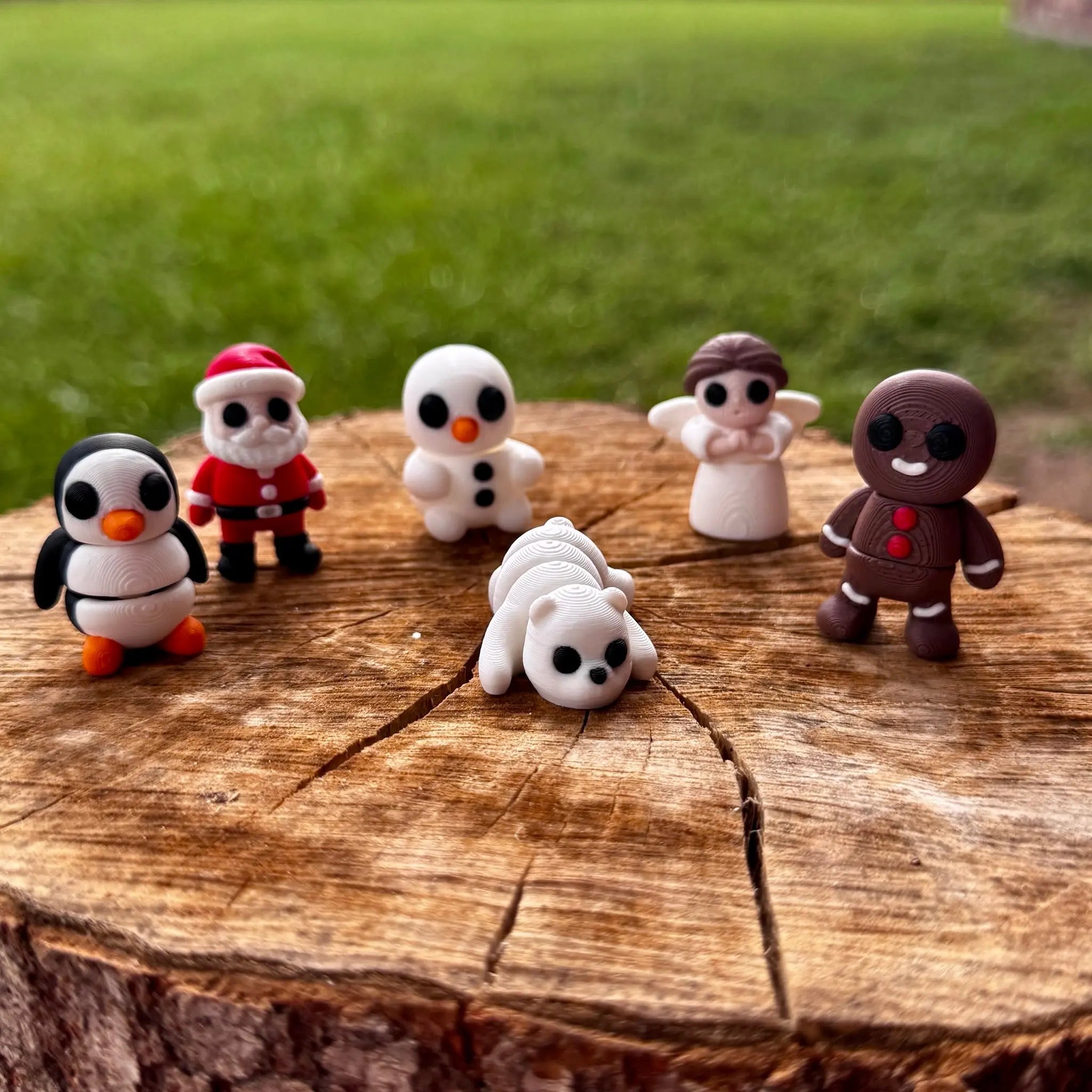 Christmas figurines on tree stump: penguin, Santa, snowman, polar bear, angel, gingerbread man. Miniature Christmas ornaments.