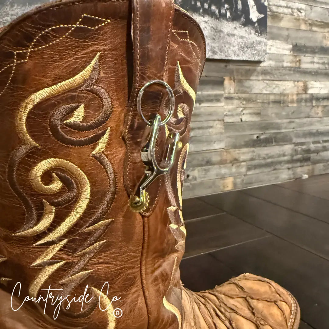 Brown cowboy boot with gold stitching and a silver spur keychain attached.