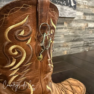 Brown cowboy boot with gold stitching and a silver spur keychain attached.