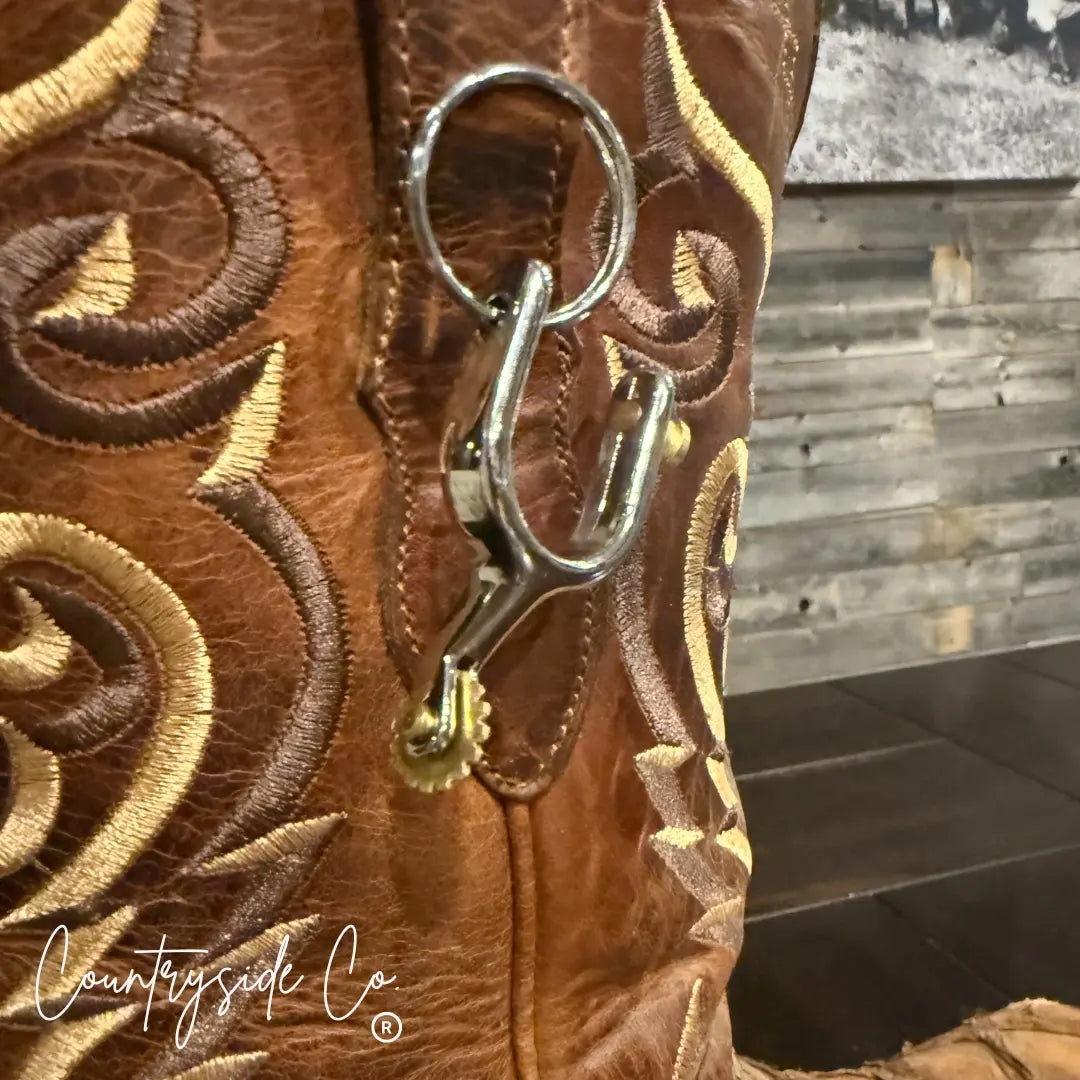 Close-up of a cowboy boot keychain with ornate stitching and a metal spur charm.