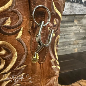 Close-up of a cowboy boot keychain with ornate stitching and a metal spur charm.