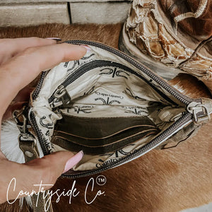 Interior view of a brown cowhide wristlet with credit card slots and a zipper.