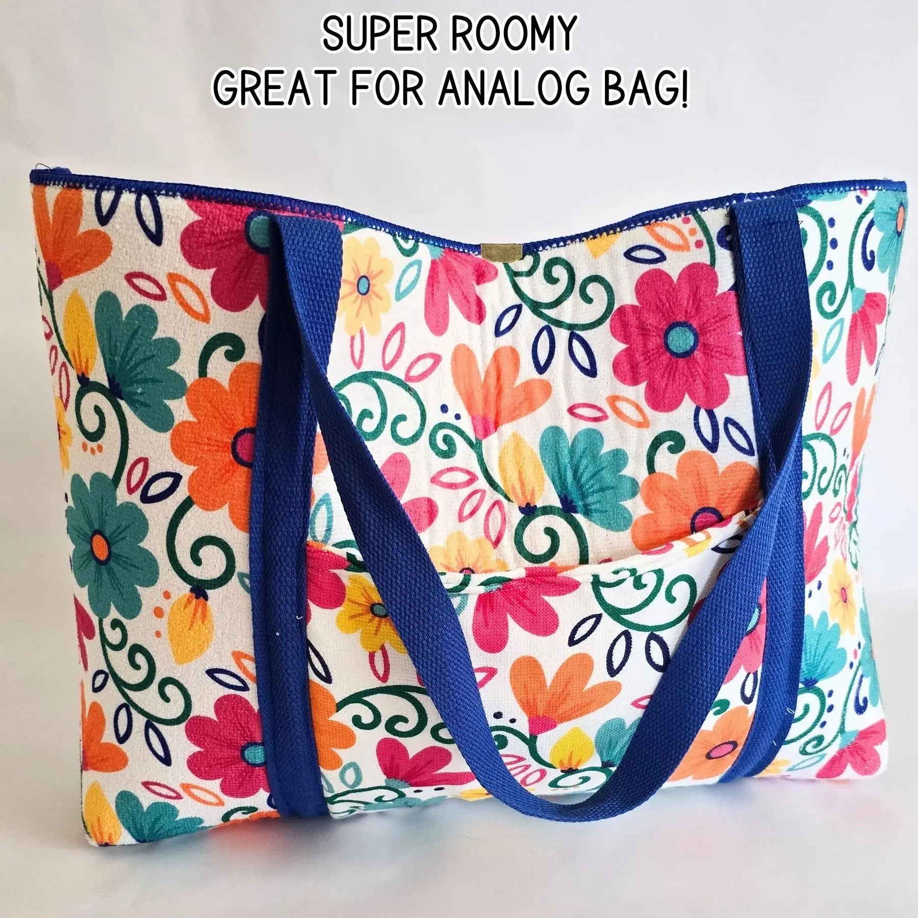 Colorful floral tote bag with blue straps and an open front pocket.