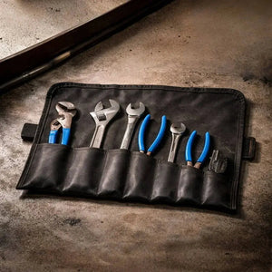 Black leather tool roll holding wrenches and pliers.