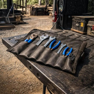 Leather tool roll with adjustable wrenches and pliers on a truck bed.