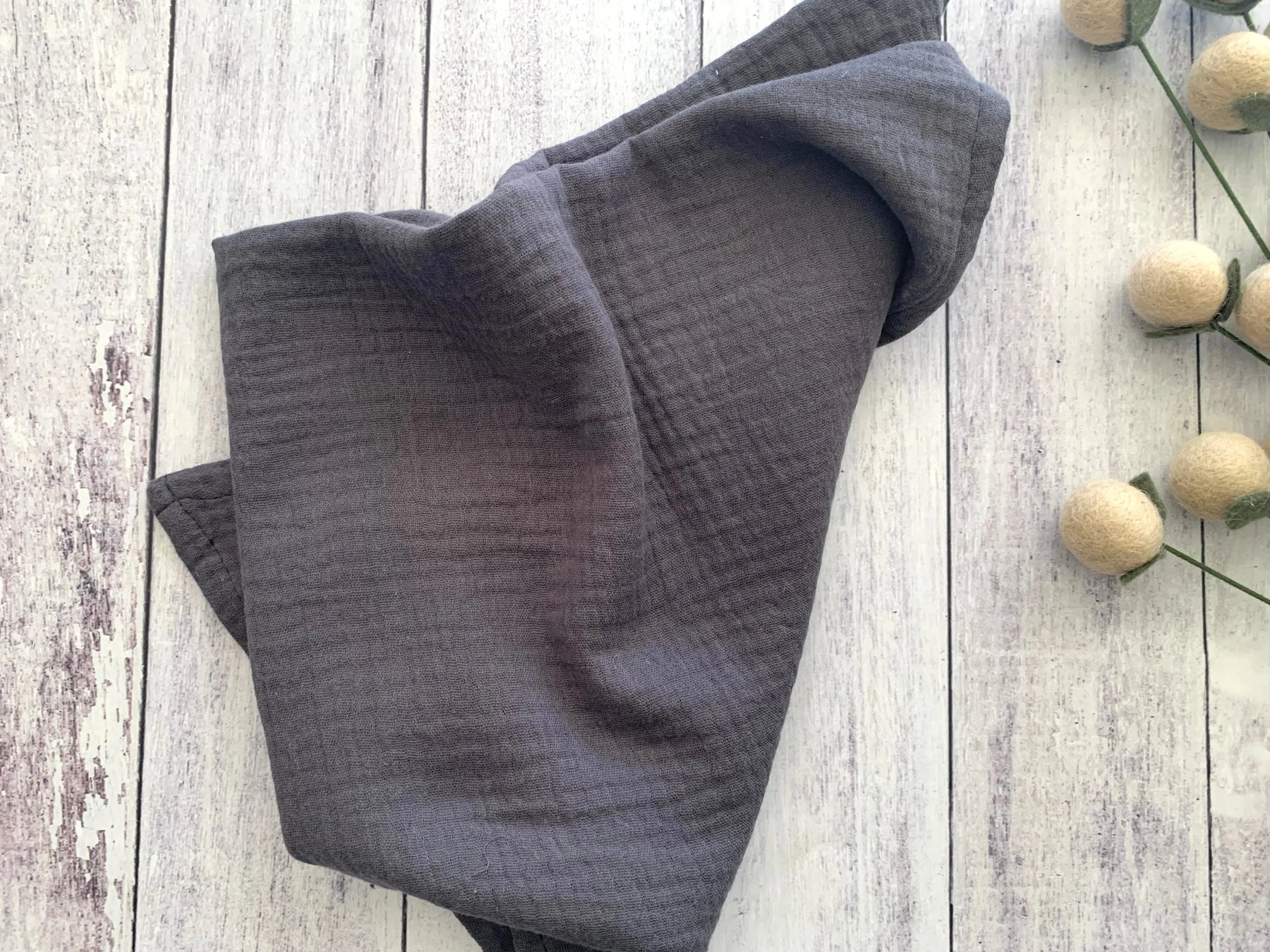 Dark grey cotton crinkle cloth napkins folded on a white wooden background.
