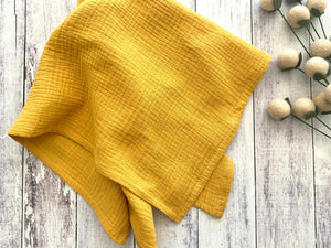 Yellow crinkle cotton napkins on a white wood background