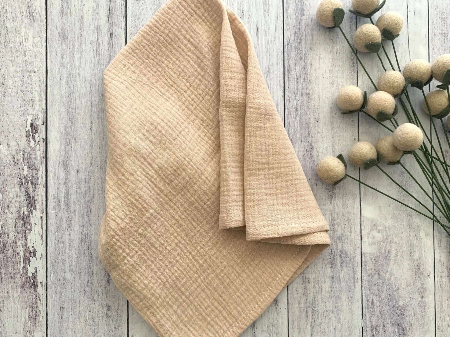 Beige cotton crinkle cloth napkins in a set of four folded on a wooden surface.