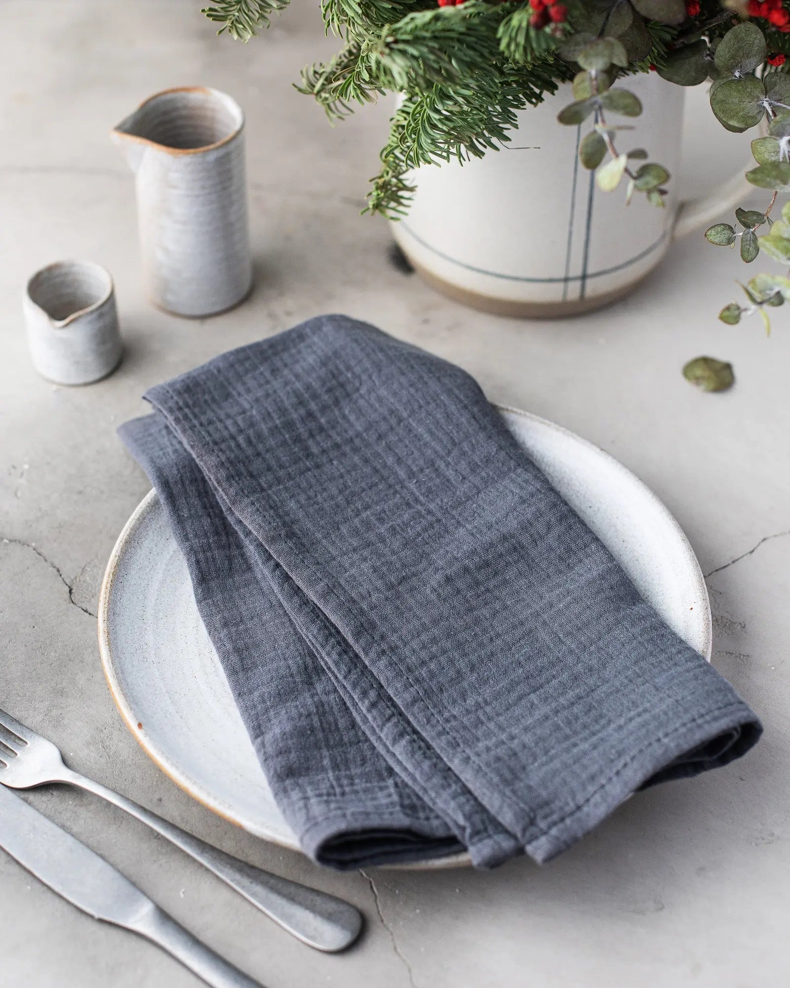 Dark gray cotton crinkle napkins folded on a white plate with silverware.