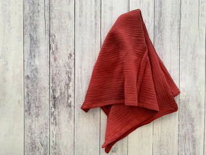 Red crinkle cloth napkins draped on a distressed white wooden background.