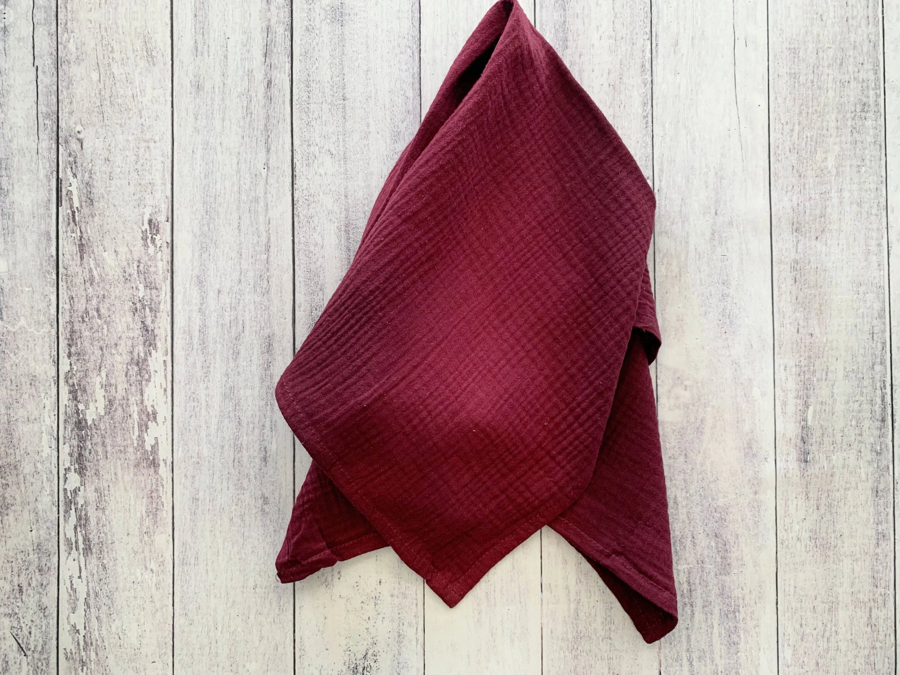Cotton crinkle cloth napkins, set of four, burgundy color on wood background.