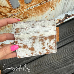 Cowhide credit card holder with "Countryside Co." tag on wooden surface