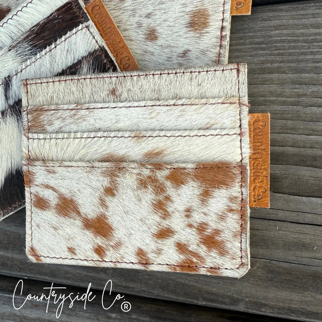 Cowhide credit card holder with brown and white patches and Countryside Co. tag.
