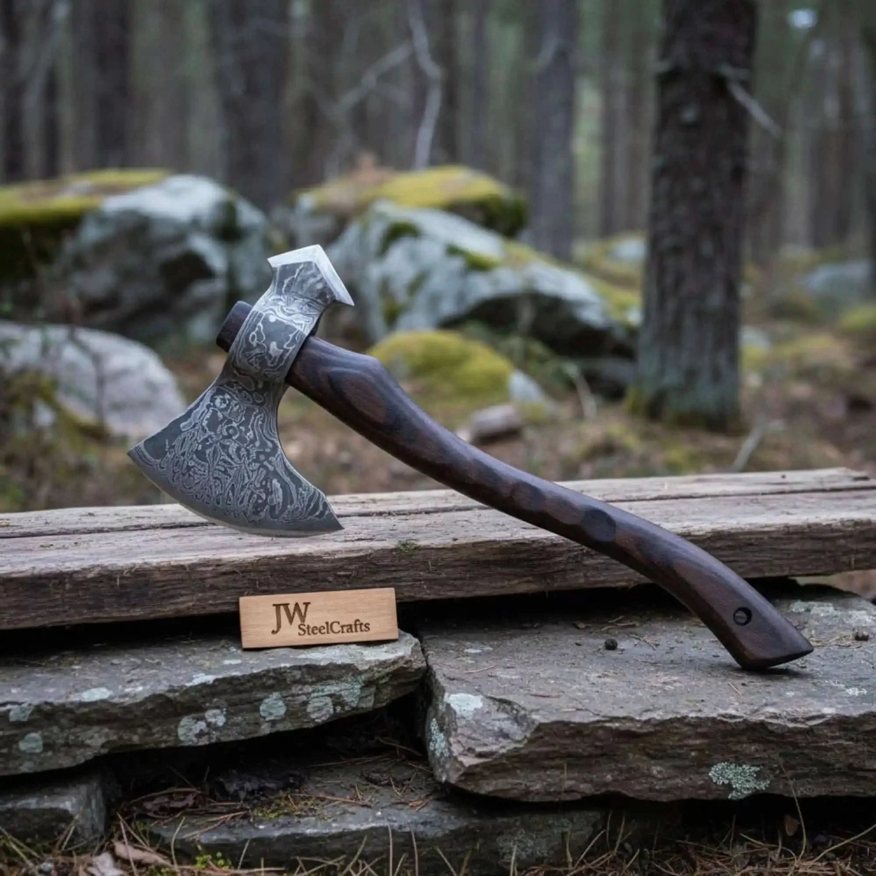 Damascus steel axe head with wood handle on rustic wood surface