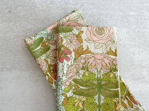 Pink and green floral cloth napkins with dragonflies on a light background.