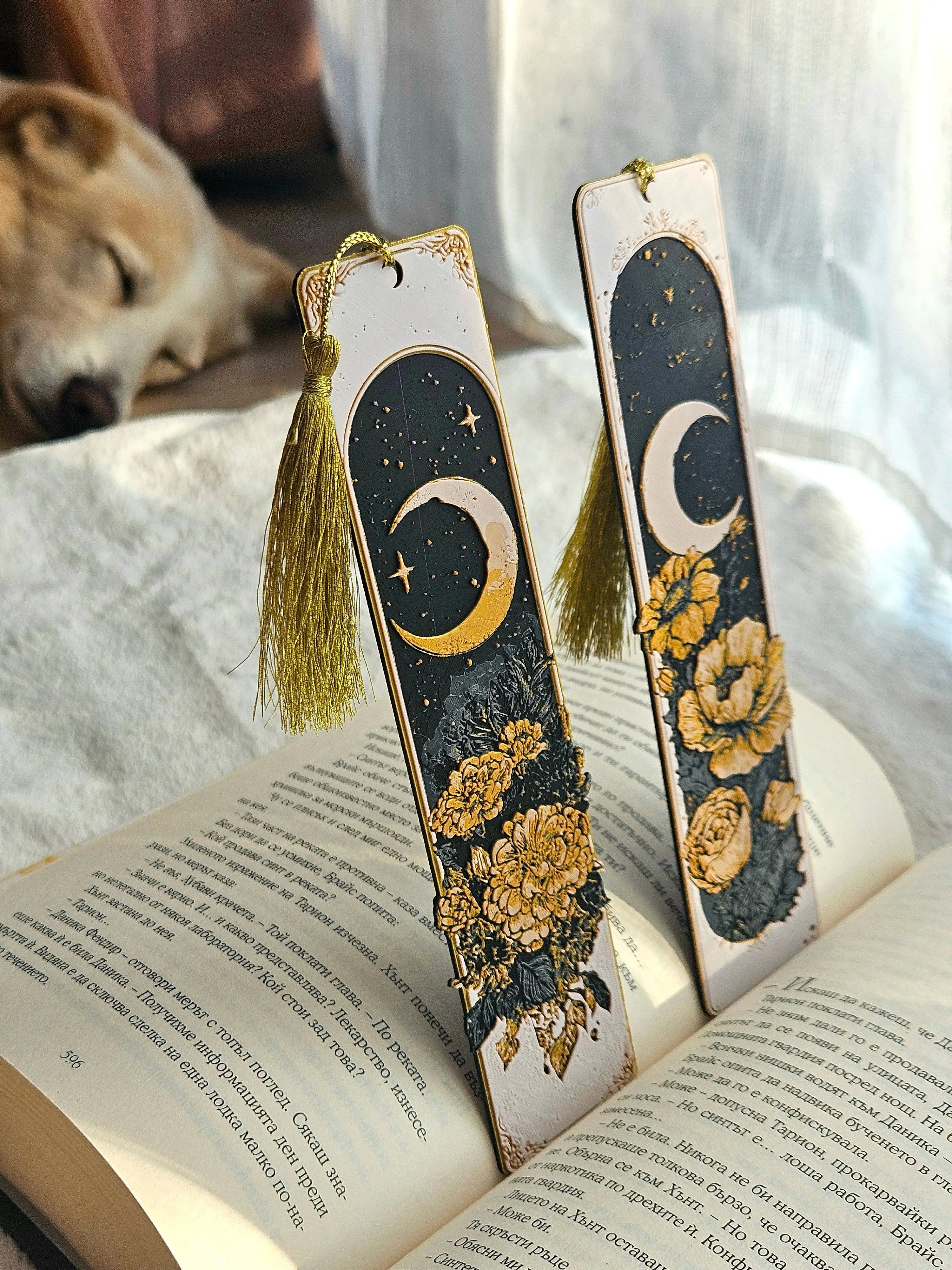 Celestial moon bookmarks with gold tassels on a book. Handmade crescent moon and floral design.