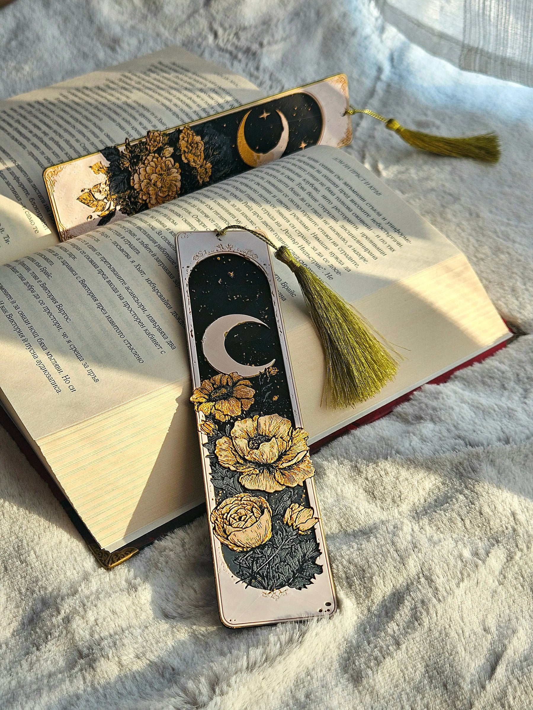 Celestial bookmarks: crescent moon and floral design with golden tones on book.